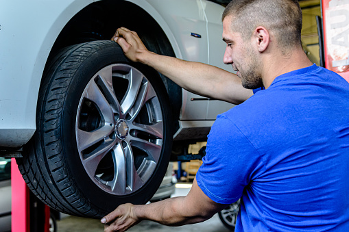 A Car Mechanic is Replacing the Tire of the Car in a Car Service Using Working Tools.