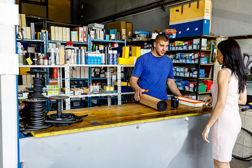 Cheerful cute couple choosing new tablet in electronic store. Looking at tablet and smiling.