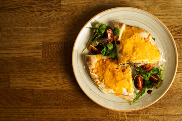 Ham and cheese tortilla sandwich with vegetables on a wooden table