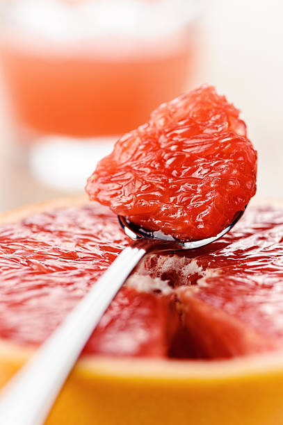 Piece of red grapefruit on the spoon, citrus dessert stock photo