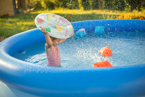 Little girl playing in the pool on a hot summer day