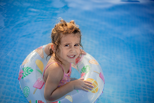 Little girl playing in the pool on a hot summer day