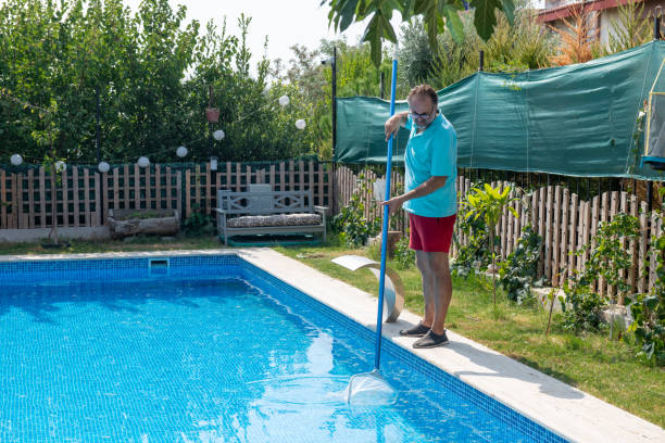 istock Man in flip flops cleaning the swimming pool with a net. 1622841002
