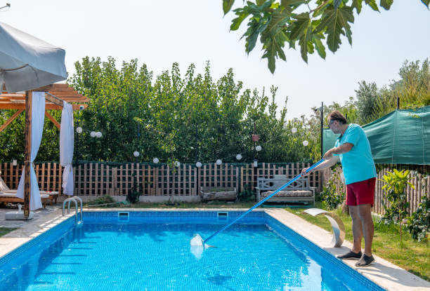 istock Man in flip flops cleaning the swimming pool with a net. 1622842158