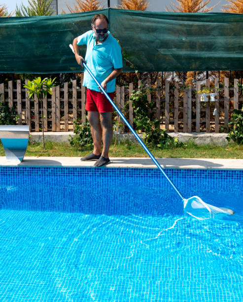 istock Man in flip flops cleaning the swimming pool with a net. 1622842698
