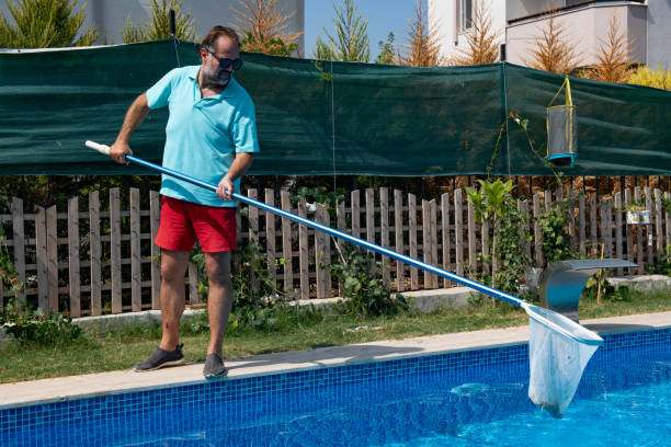 istock Man in flip flops cleaning the swimming pool with a net. 1622845453
