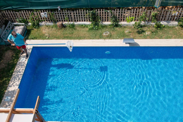 istock Man in flip flops cleaning the swimming pool with a net. 1622851982