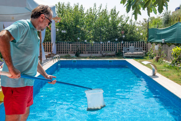 istock Man in flip flops cleaning the swimming pool with a net. 1622852073