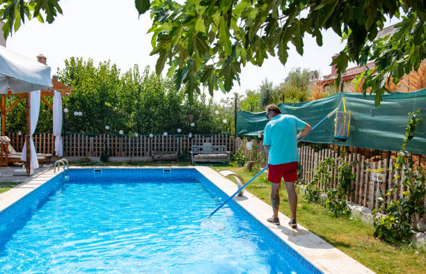 istock Man in flip flops cleaning the swimming pool with a net. 1622852148