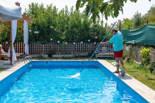 istock Man in flip flops cleaning the swimming pool with a net. 1622855407