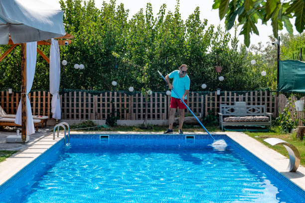 istock Man in flip flops cleaning the swimming pool with a net. 1622856492