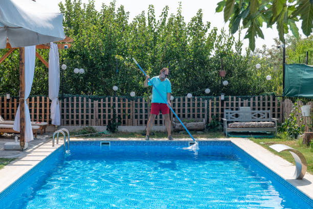 istock Man in flip flops cleaning the swimming pool with a net. 1622857057