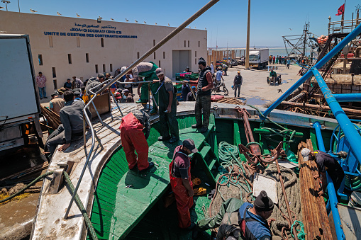 Essaouira, Morocco - August 2, 2023: On the quay of the port, the men of a fishing boat returning from the sea, prepare to unload the fish that will be transported to the market.