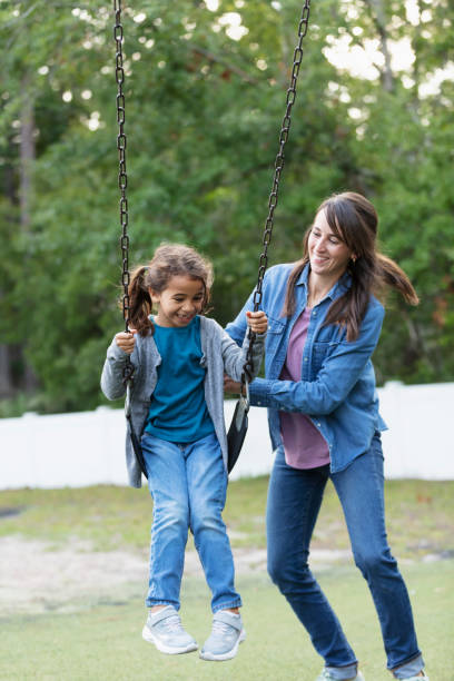 istock Mother pushing daughter on swing on playground 1622881569