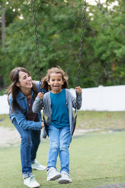 istock Mother pushing daughter on swing on playground 1622881570
