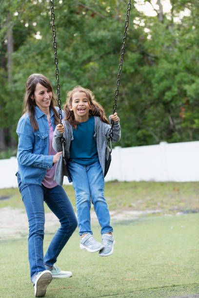 istock Mother pushing daughter on swing on playground 1622882100