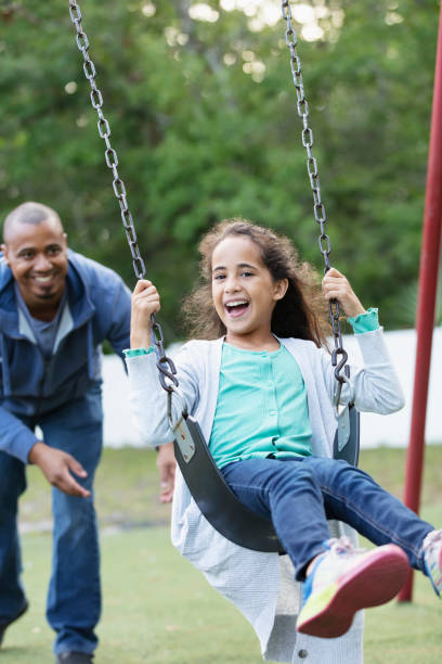 istock Father pushing daughter in swing on playground 1622883732
