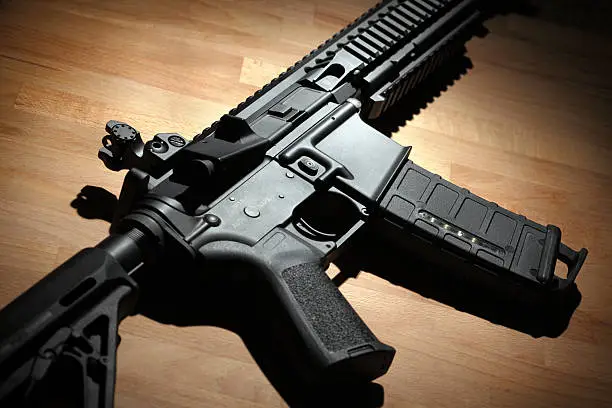 Modern custom AR-15 (M4A1) carbine on a wooden surface. Studio shot