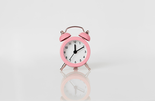 Pink alarm clock on white background.