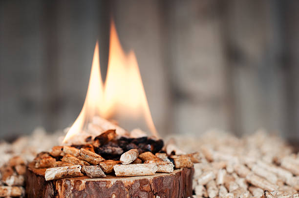 Pine pellets on wooden slice in flames- selective focus on foreground