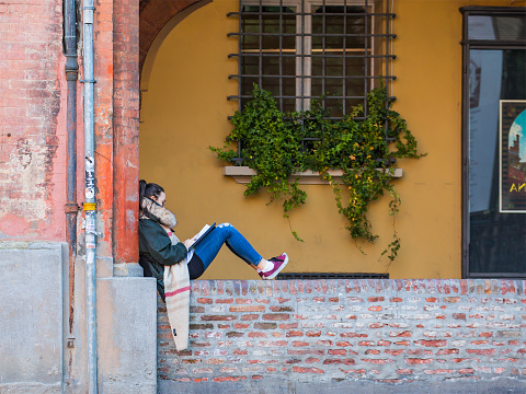 Bologna, italy - March 11, 2015: A young girl college student is sitting outside the school waiting for the exam