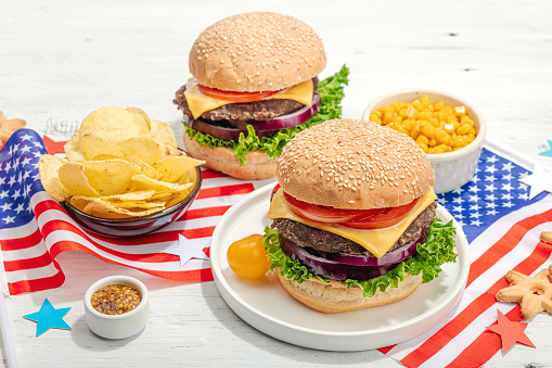 Homemade burgers. An American classic, traditional food for picnic, party or celebration Independence Day. Hard light, dark shadow, flat lay, white wooden background, close up