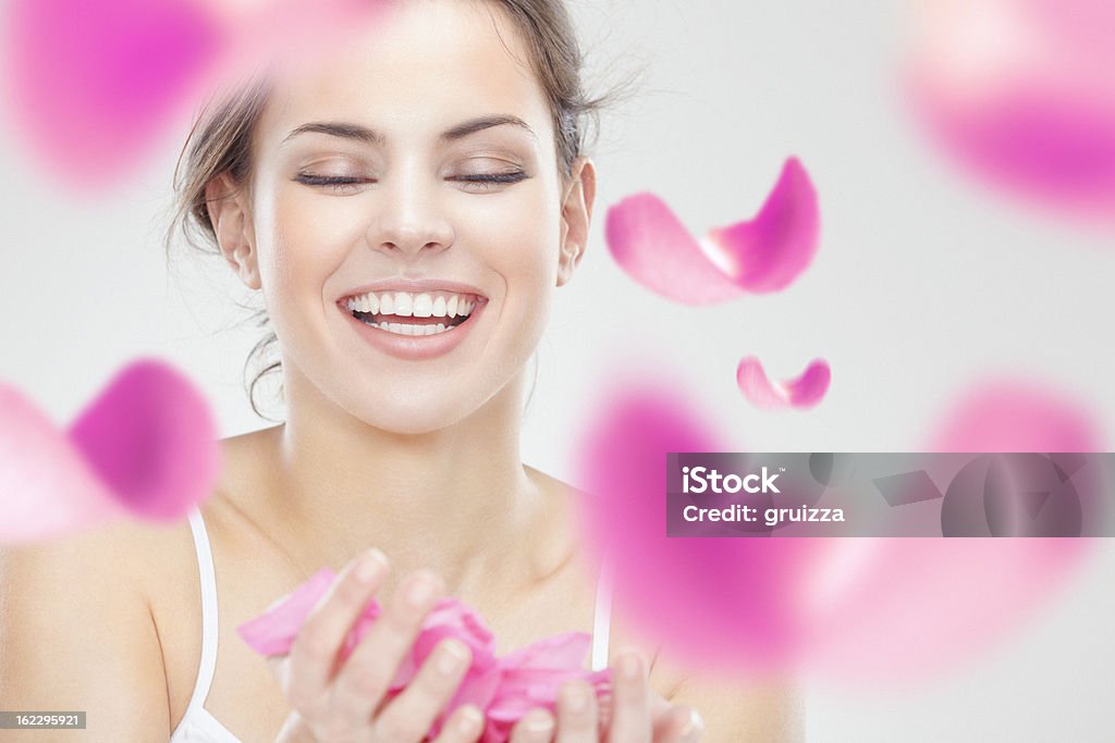 美しい若い笑顔の女性に囲まれたピンクのバラの花びらのご利用 - 人の顔のロイヤリティフリーストックフォト