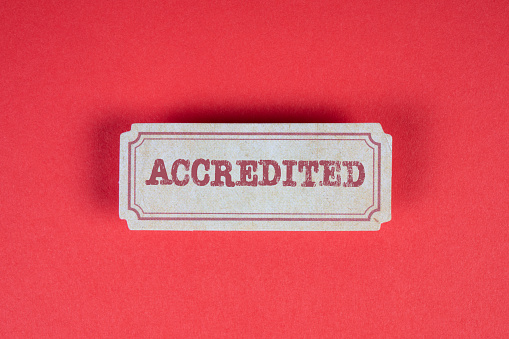 ACCREDITED. Cardboard sticker with text on a red background.
