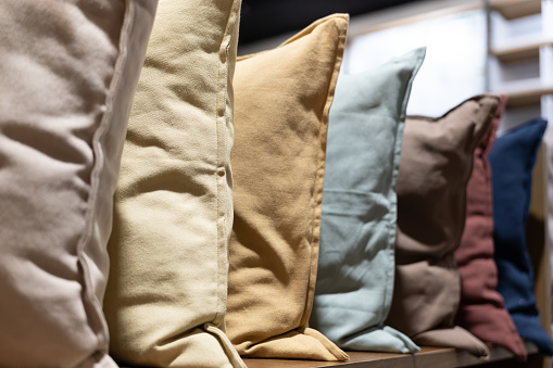 Row of decorative pillows on a store shelf. Many pillows are in a row.