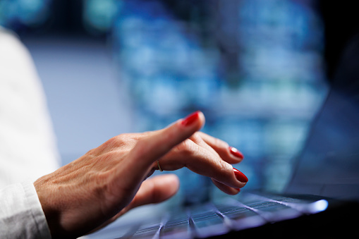 Senescent worker using laptop, setting up high bandwidth dedicated multiplayer gaming servers in high tech workspace to accommodate more traffic from worldwide locations and avoid low ping, close up