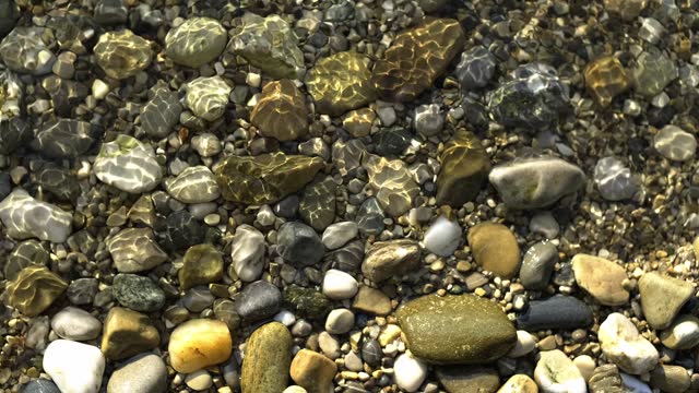 scene of a lakeshore with pebbles from above, small soft waves