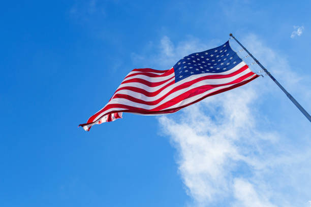 istock American Flag blowing in the wind with a blue sky 1623028690