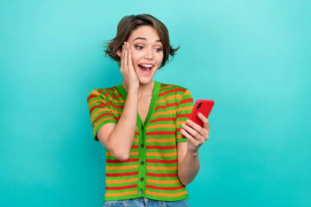 Photo of adorable impressed lady wear striped cardigan reading iphone apple samsung gadget arm cheek isolated teal color background.