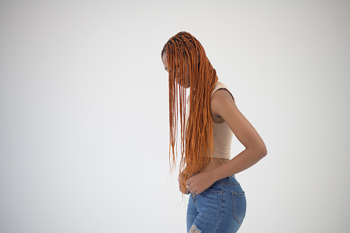Young African Woman obscured face showing her long red coloured braided hair and crop top Studio Portrait