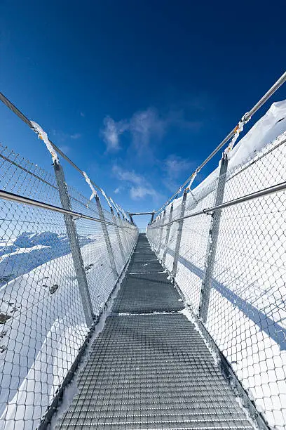 suspension bridge at mount titlis, swiss alps, switzerland. it´s the highest suspension bridge in europe, it´s on the top of mount titlis in 3041m above sea level. it´s a steel cable bridge around 500m over the abyss. 