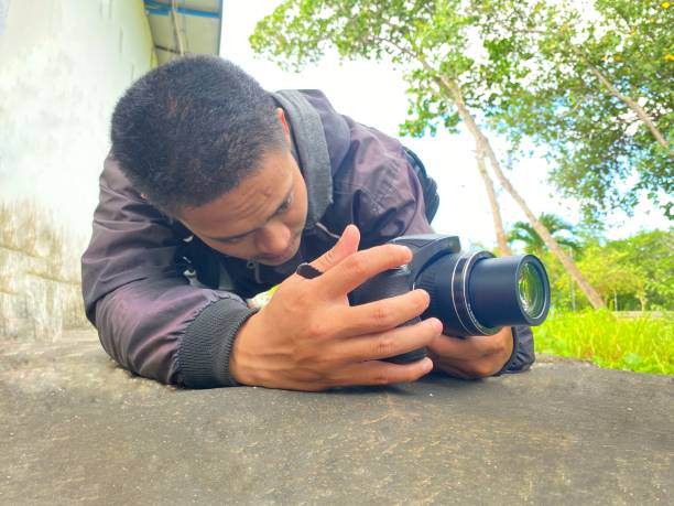istock a man squatting taking photos using a digital camera in the park. 1623054840