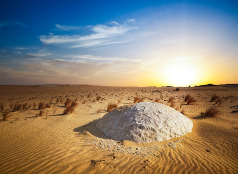 sunset in the white desert of egypt - in front of a small limestone rock