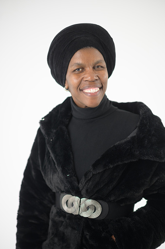 Beautiful mid aged smiling African woman with head covering and coat studio portrait