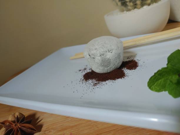箸と木製の背景を持つ白い皿にカプチーノ餅アイスクリーム。セレクティブフォーカスで写真をクローズアップします。春または夏のロマンチックなコンセプト