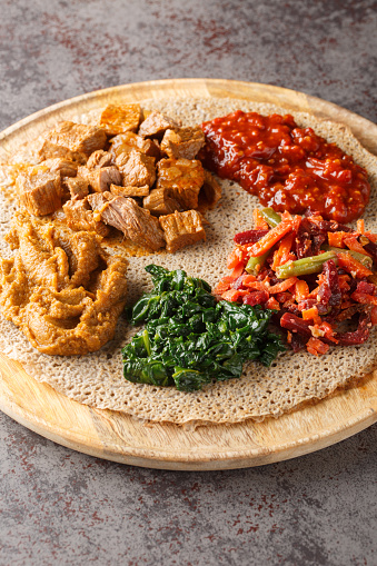 Injera firfir flatbread typical Ethiopian breakfast food close up on the wooden board. Vertical