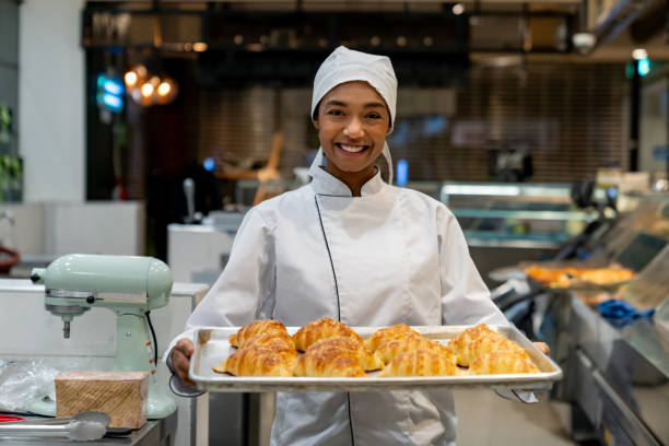 istock Happy baker holding a tray of fresh bread while working at the bakery 1623084521