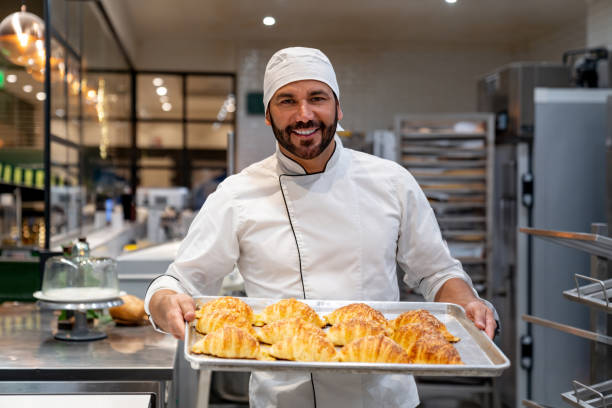istock Happy baker holding a tray of fresh bread while working at the bakery 1623084532