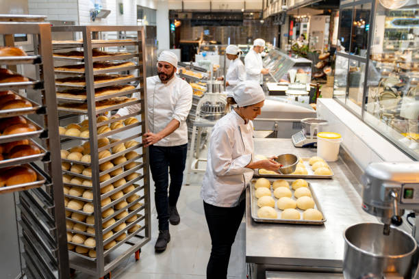 Group of employees working at a bakery baking bread Group of Latin American employees working at a bakery baking fresh bread - small business concepts commercial kitchen photos stock pictures, royalty-free photos & images