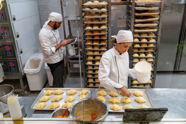 istock Female baker spreading sugar on some croissants 1623086787