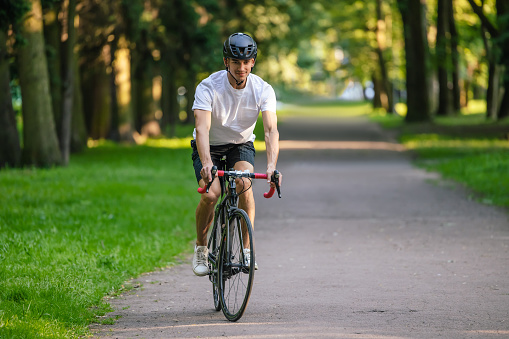 Healthy lifestyle. Young man in protective hemlet riding a bike in a park
