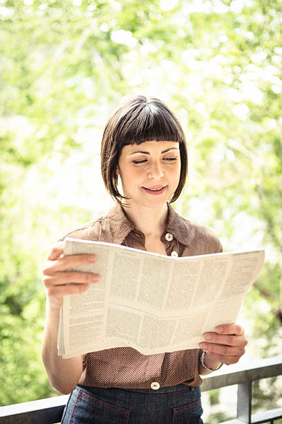 istock Smiling woman reading a newspaper 162310474