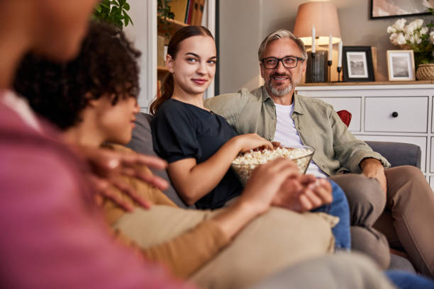 istock Family relaxing on a couch together, talking and eating popcorn. 1623105542