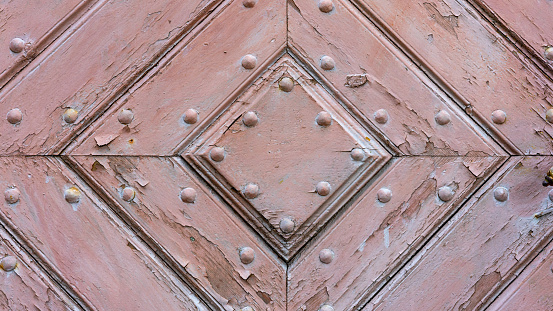 Close-up of an old, church wooden door. The door is made from planks of wood that have been weathered by the elements over time, giving it a rustic look.