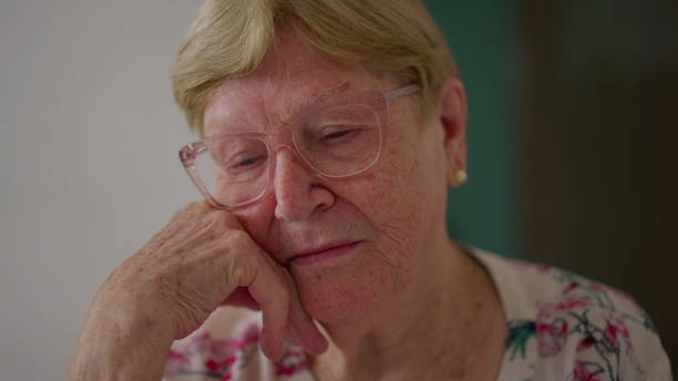 istock Contemplative elderly senior woman in 80s standing by window looking out while remembering past memories, pensive thoughtful older lady 1623130346