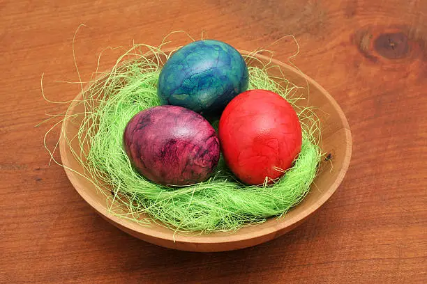 three easter eggs in wooden bowl